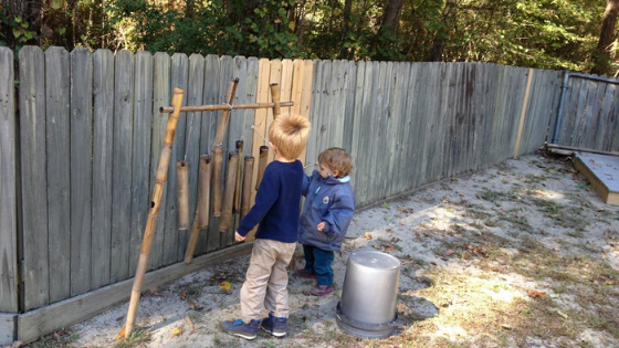 A young boy standing next to a fenceDescription automatically generated