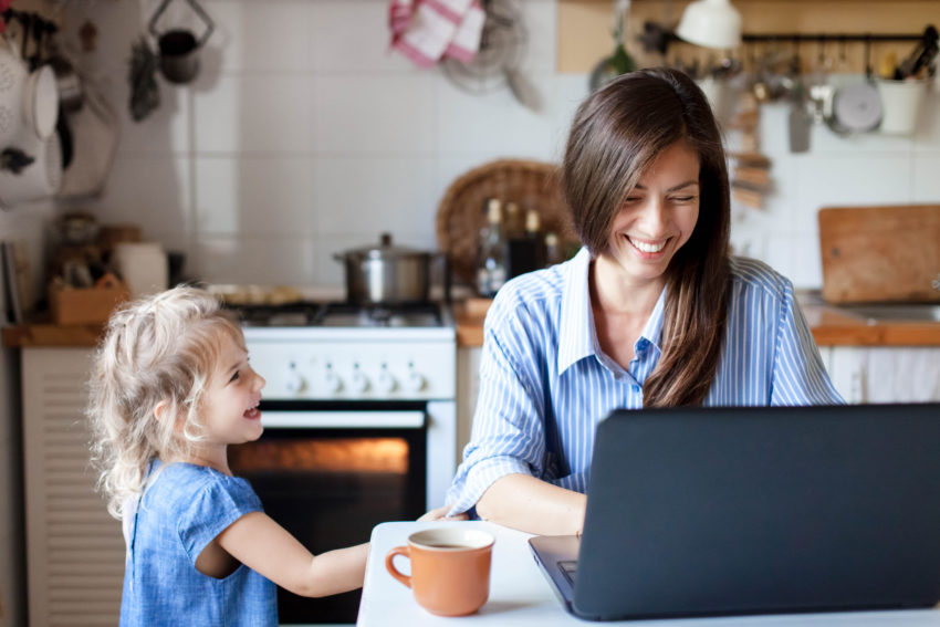 girl smiling at her mom as she works on her laptop