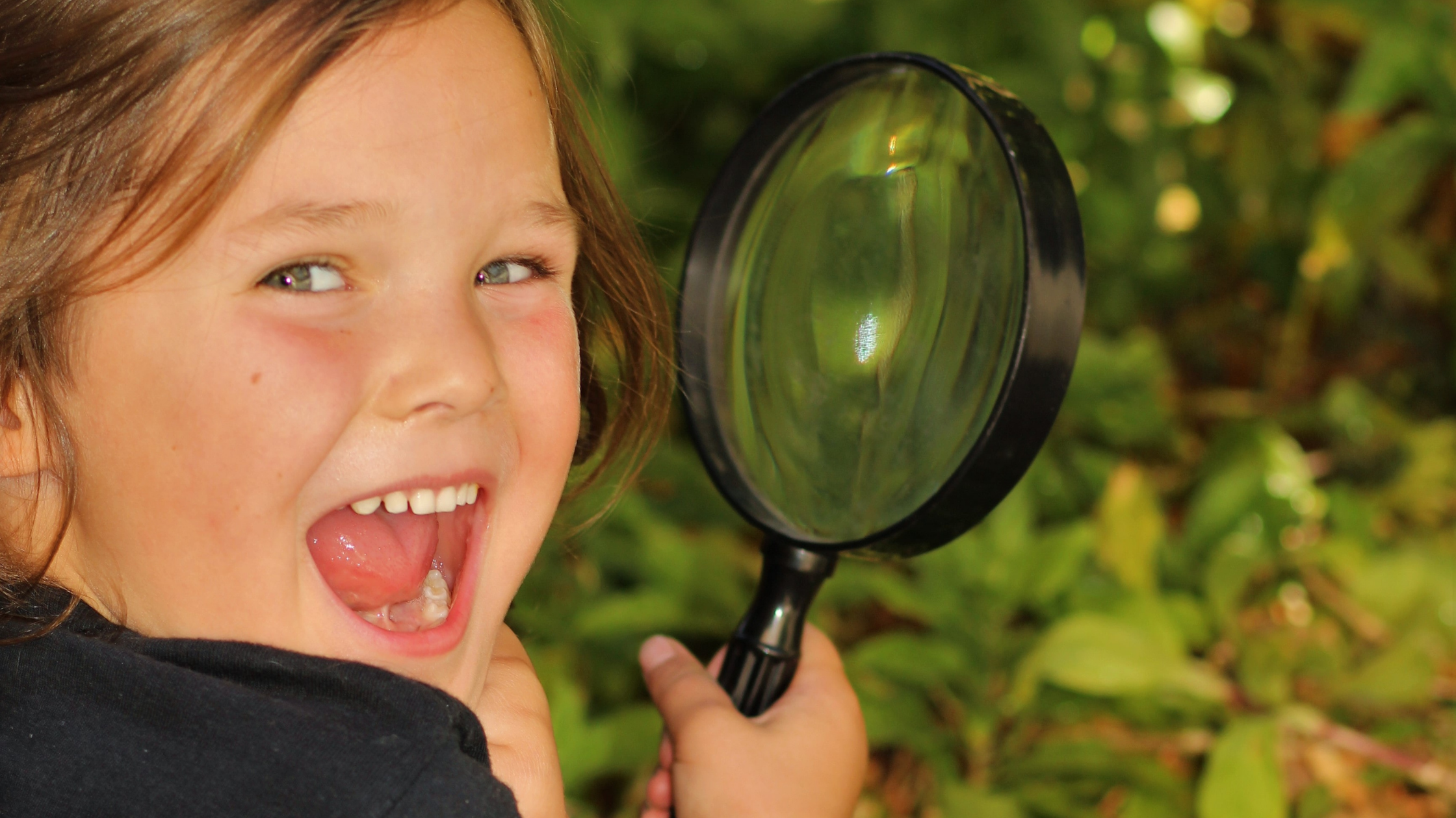 girl smiling with a magnifying glass in hand