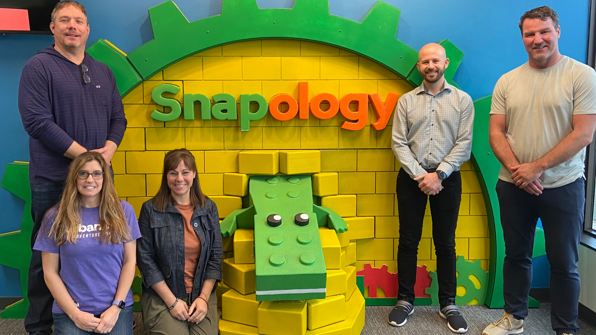snapology staff members posing in front of a branded wall