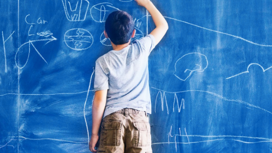 child drawing with chalk on a wall